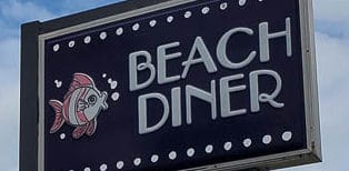 Close up of Beach Diner sign in Atlantic Beach, Florida showing the tropical fish and bubbles logo next to the words Beach Diner in  retro-cool font with dots for lights in a row at the top and bottom of the sign