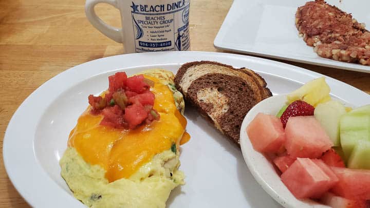 Mexican omelette at Atlantic Beach Diner - a chicken omelette topped with cheddar and salsa, plated with a side of mixed fruit and swirled rye toast, mug of coffee in background